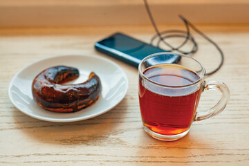 A charging smartphone, a glazed cookie and a cup of Turkish tea on a table in an airport cafe. Traveler's pause before a flight.