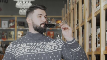 Handsome man savoring red wine at a vibrant wine supermarket