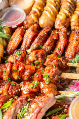  A close-up of a delectable barbecue spread featuring sticky chicken wings, skewered meat, and...