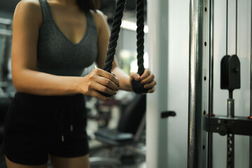 Close-up of woman’s hands gripping a rope attachment during triceps pushdown exercise at gym