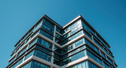 Obraz premium Office Building Exterior with Glass Windows Against Clear Blue Sky