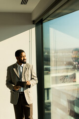 Business professional engages with a tablet while enjoying a sunny afternoon by a large window