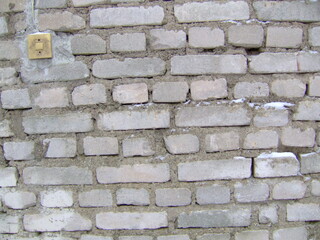 Brick wall with rough texture in an urban setting, showcasing natural aging and historical character