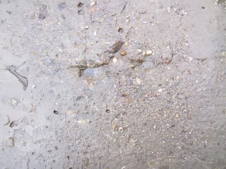 Natural texture of a worn-out surface featuring gravel and dirt collected in a weathered area under soft daylight