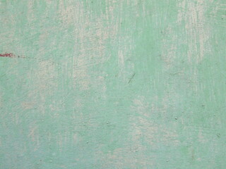 Smooth textured surface of faded mint green wall reveals layers of paint in an urban setting during daylight