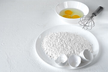 Flour, eggs, a whisk for beating the dough. Horizontal frame.