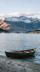 Tranquil reflective lake with weathered green boat and snow-capped mountain backdrop