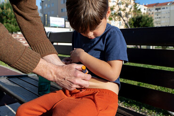 Diabetes management: parent assisting child with insulin injection outdoors