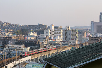 夕暮れの横浜上大岡の市街地をバックに走る電車