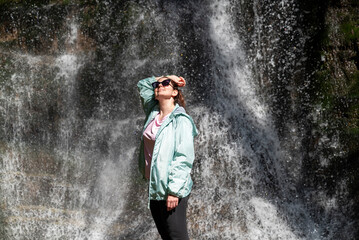 Relaxed woman breathing fresh air in front of a waterfall 