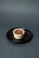 Bowl with rice pudding on dark background. Creamy rice with pistachio nuts and chocolate. Copy space. Top view