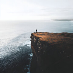 A man stands on a cliff overlooking the ocean