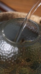 Gently pouring water into a beautifully designed glass teapot creates a serene ambiance. Media