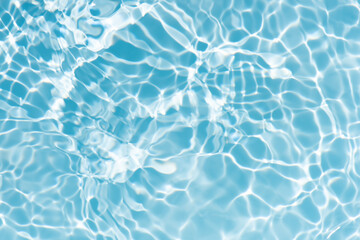 Blue water with ripples on the surface. Defocus blurred transparent blue colored clear calm water surface texture with splashes and bubbles. Water waves with shining pattern texture background.