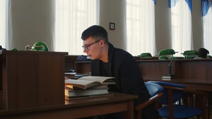 A dedicated student is completely engaged in their study while seated at the library desk. Media