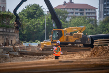 Engineer worker operations construction plans large black drainage pipe installing underground...