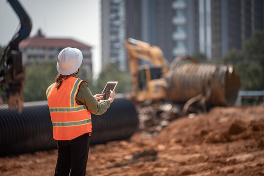 Engineer worker operations construction plans large black drainage pipe installing underground infrastructure heavy machinery importance of careful planning and teamwork in construction project.