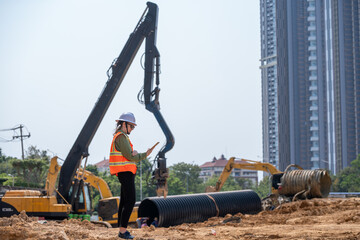 Engineer worker operations construction plans large black drainage pipe installing underground...