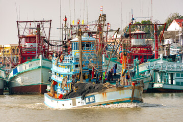 At a busy fishing harbor, numerous fishing vary in size and color boats anchored in a waterway....
