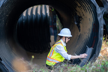 Construction surveyor or engineer working inspection damaged black corrugated pipe and construction...