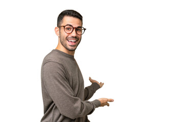 Young handsome caucasian man over isolated background extending hands to the side for inviting to...