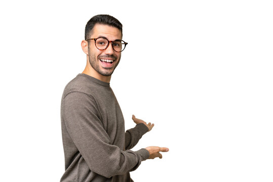 Young handsome caucasian man over isolated background extending hands to the side for inviting to come