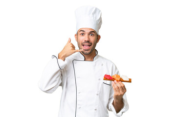 Young caucasian chef holding a sushi over isolated background making phone gesture. Call me back sign