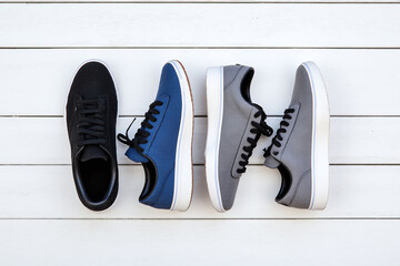 three pairs of blue and black sneakers on a white wooden floor