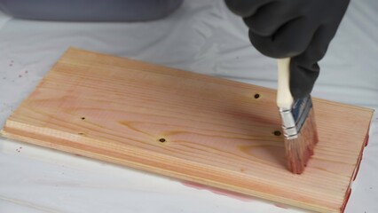A person is carefully painting a piece of wood using a brush. Creative