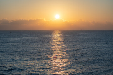 Sunset over the ocean, with the sun low on the horizon, contrast between sky and sea