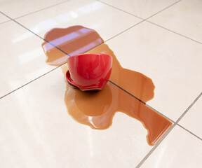Spilled coffee, coffe puddle stain on tiled floor, messy leak with fallen cup, brown drink spillage