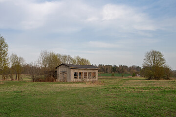 Obraz premium Wooden plank barn with latticed windows in a rural landscape