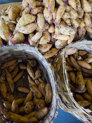 Fresh Cilembu sweet potatoes displayed in traditional woven baskets at Indonesian market, premium honey-sweet variety for authentic Asian cooking