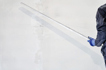 An unrecognizable man holds a metal rule for leveling plaster on walls. High quality photo