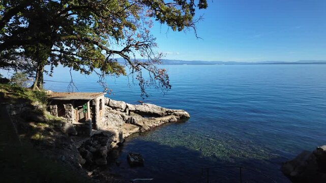 View from the Lungomare Coastal Promenade near Lovran, Croatia. Rocky coastline of the Adriatic Sea with beautiful nature and a little house. The famous seaside promenade is more then 100 years old.