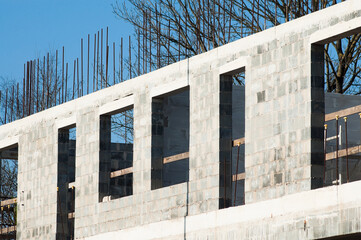 Fototapeta premium unfinished construction of an apartment building made of gray blocks, blue sky in the background