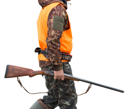 A man with a gun in his hands and an orange vest on a pheasant hunt in a wooded area in cloudy weather. Hunter with dogs in search of game.