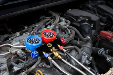 Auto mechanic's hand uses a meter to check for problems with the car's air conditioning system and...