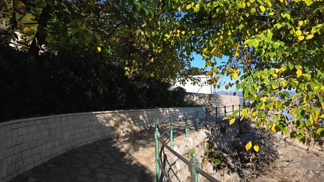 Walking on the Lungomare Coastal Promenade near Lovran, Croatia. Beautiful coastline of the Adriatic Sea with Rijeka in the background. The famous seaside promenade is more then 100 years old.