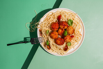 Spaghetti and meatballs with tomato sauce, basil and cherry tomatoes on a plate on a bright...