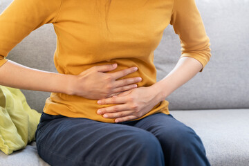 Young Asian woman suffering stomach pain from food poisoning.