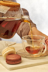 Pouring a delightful cup of tea paired with elegant macarons for a perfect afternoon break