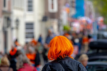 Colourful of King’s Day (Koningsdag in Dutch) Selective focus of a women wearing orange hair wig walking on the street, Outdoor celebration birthday party of the King, National holiday in Netherlands.