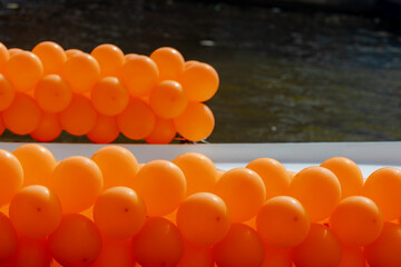 Colourful of King’s Day (in Dutch: Koningsdag) Selective focus of orange balloons decorated outside building and along street, Celebration of the birthday of the King, National holiday in Netherlands.