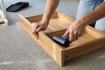Close-up of a man assembling furniture with a cordless drill. DIY furniture assembly. Instructions