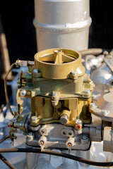 Close-up of a K126I carburetor, a complex mechanical component of an engine, featuring various levers, screws, and linkages.