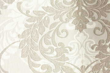 Detailed wallpaper background featuring an intricate floral and swirl design in beige and ivory tones, creating an elegant texture.