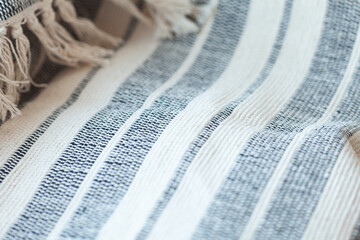 Close-up of a striped cotton throw with fringe. The white and charcoal colored stripes are uneven,...