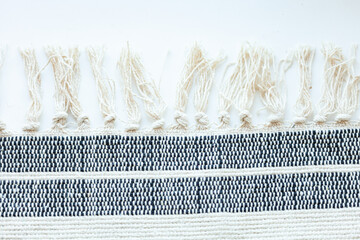 Detailed shot of woven fabric with textured fringe, showcasing craftsmanship and textile design against a white background.