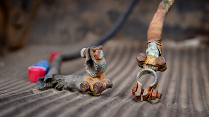 Rusted and corroded positive and negative car battery terminals with attached cables.